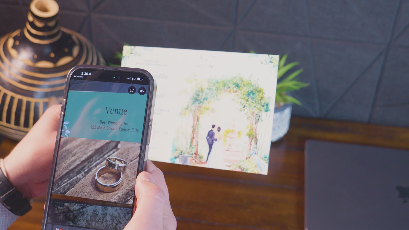 Phone camera scanning a printed wedding invitation to launch a personalized video message overlaid on the card